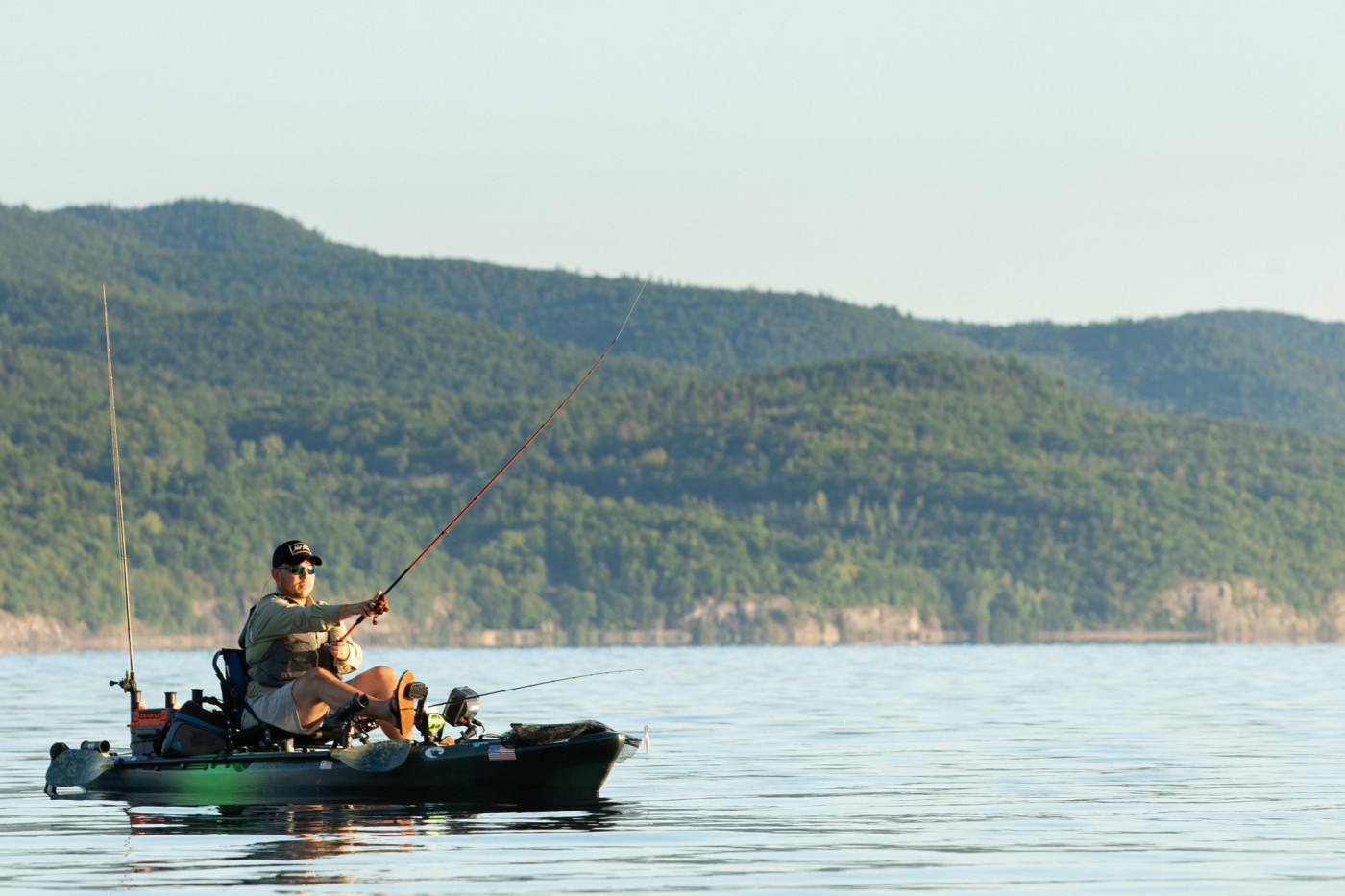 A man casts from a kayak on an Adirondack lake